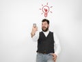 Young man with black beard is posing and looking at his smartphone in front of white background with different emotions Royalty Free Stock Photo