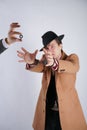 Young man in a black business suit and beige fashion coat with a stylish hat stands in police handcuffs on a white solid Studio ba Royalty Free Stock Photo