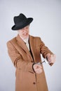 Young man in a black business suit and beige fashion coat with a stylish hat stands in police handcuffs on a white solid Studio ba Royalty Free Stock Photo