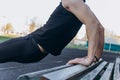 A young man in black clothes is exercising outdoors close up. fitness athlete on the sports field. training with projectiles. warm Royalty Free Stock Photo