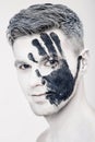 Young man with black hand print on white face. Closeup Portrait. Professional Fashion Makeup. fantasy art makeup Royalty Free Stock Photo