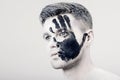 Young man with black hand print on white face. Closeup Portrait. Professional Fashion Makeup. fantasy art makeup Royalty Free Stock Photo