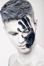 Young man with black hand print on white face. Closeup Portrait. Professional Fashion Makeup. fantasy art makeup Royalty Free Stock Photo