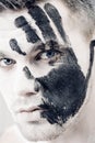 Young man with black hand print on white face. Closeup Portrait. Professional Fashion Makeup. fantasy art makeup Royalty Free Stock Photo