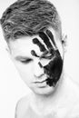 Young man with black hand print on white face. Closeup Portrait. Professional Fashion Makeup. fantasy art makeup Royalty Free Stock Photo