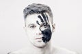 Young man with black hand print on white face. Closeup Portrait. Professional Fashion Makeup. fantasy art makeup Royalty Free Stock Photo