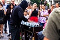 A young man in a black hood playing music on glasses filled with water Prague