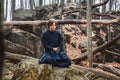 Young man in black kimono with a sword meditates and concentrates on rocks and forest background. Place for text or advertising Royalty Free Stock Photo