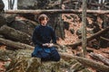 Young man in black kimono with a sword meditates and concentrates on rocks and forest background. Place for text or advertising