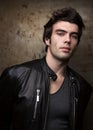 Young man in black leather jacket posing by metal walls. Portrait of the brunette Royalty Free Stock Photo