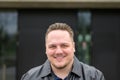 Young man in a black leather jacket and slicked back hair looking friendly to camera