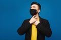 Young man in black protective mask with throat sore, isolated. Handsome men holds hands on his neck because of throat Royalty Free Stock Photo