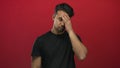 Young man in black shirt with a frustrated expression against an isolated red background Royalty Free Stock Photo