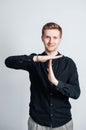 Young man in a black shirt shows a time out sign with his hands on a white background. Copy, empty space for text Royalty Free Stock Photo