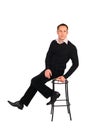 Young man in black sits on stool Royalty Free Stock Photo