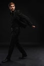 Young man in black suit full body portrait against black background. Royalty Free Stock Photo