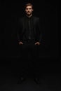 Young man in black suit full body portrait against black background. Royalty Free Stock Photo