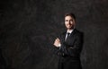 Young man in a black suit on a gray background. Bearded businessman smiling Royalty Free Stock Photo