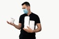 Man in a black t-shirt with a blue medical mask and toilet paper on an isolated white background