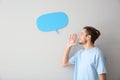 Young man and blank speech bubble on light background Royalty Free Stock Photo