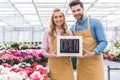 Young man and blonde woman holding Open board by flowers Royalty Free Stock Photo