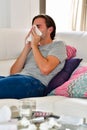 a young man blowing his nose in a napkin while lying on a sofa on an out of focus background. Hygiene and relaxation concept Royalty Free Stock Photo