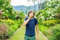 Young man blowing nose in front of blooming tree. Spring allergy concept Royalty Free Stock Photo