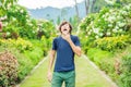 Young man blowing nose in front of blooming tree. Spring allergy concept