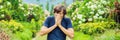 Young man blowing nose in front of blooming tree. Spring allergy concept BANNER, LONG FORMAT Royalty Free Stock Photo