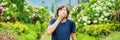 Young man blowing nose in front of blooming tree. Spring allergy concept BANNER, LONG FORMAT Royalty Free Stock Photo