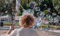 Young man blowing soap bubbles outdoor in summer time