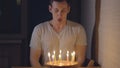 Young man blows out candles on a festive cake