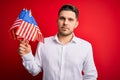 Young man with blue eyes holding flag of united states of america over red isolated background with a confident expression on Royalty Free Stock Photo