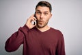 Young man with blue eyes speaking on the phone having a conversation on smartphone scared in shock with a surprise face, afraid Royalty Free Stock Photo