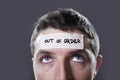 Young man with blue eyes and tape text out of order on forehead in dry empty mind