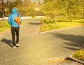 Young man in blue jacket with sports bag, walking in Park, rear view, on Sunny summer day Royalty Free Stock Photo