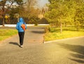 Young man in blue jacket with sports bag, walking in Park, rear view, on Sunny summer day Royalty Free Stock Photo