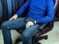 A young man in a blue jumper sits in a chair in the trading floor of a clothing store