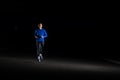 Young Man in Blue Running at Night. Urban Running. Healthy Lifestyle and Sport Concept