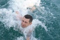 Young man in the blue sea struggling with the waves