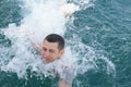 Young man in the blue sea struggling with the waves