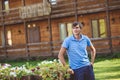 A young man in a blue shirt and blue shorts near decorative wooden carts with flowers, on a background of rustic style