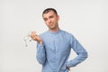 Young man in blue shirt standing disorientated bewildered isolated on gray wall background. Decision making concept.