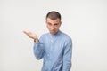 Young man in blue shirt standing disorientated bewildered isolated on gray wall background. Decision making concept.