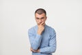 Young man in blue shirt standing disorientated bewildered isolated on gray wall background. Decision making concept.