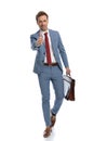 Young man in blue suit holding suitcase and making thumbs up gesture Royalty Free Stock Photo