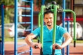 Handsome smiling man in blue t-shirt doing chest exercises sitting on butterfly training machine at public playground. Copy space Royalty Free Stock Photo