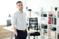 A young man stands near a table in the office, his hands in his pockets. Royalty Free Stock Photo