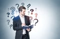 Young man with book and question marks