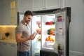 Man with bottles of yoghurt near open refrigerator in kitchen Royalty Free Stock Photo